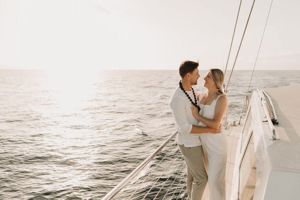 couple standing on side of the boat out at sea for sunset cruise
