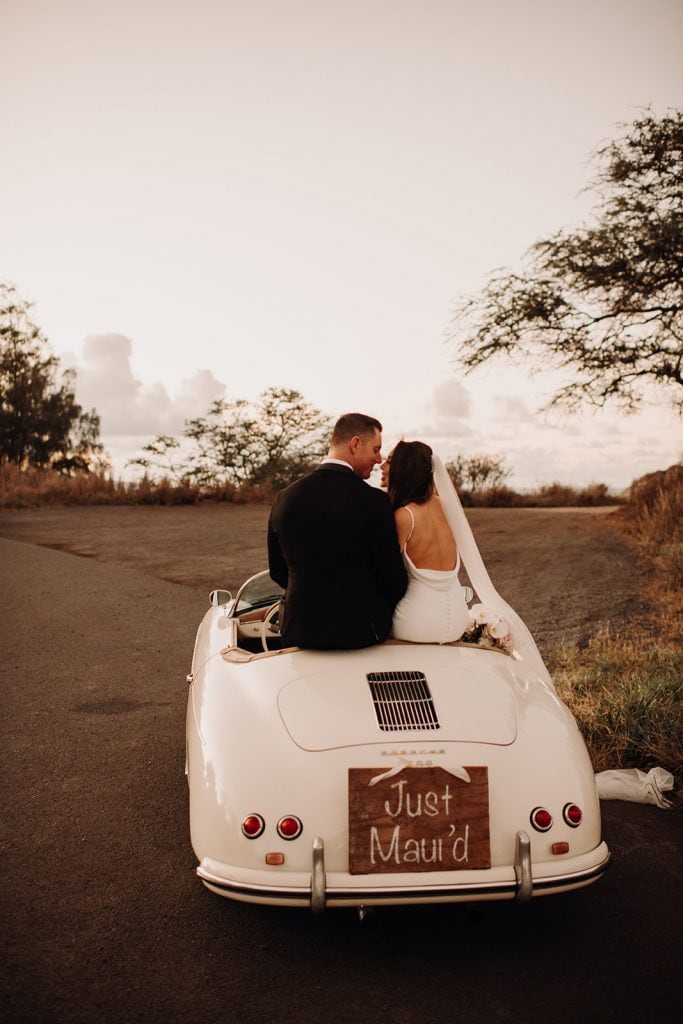 couple sitting on vintage porsche with 'just maui'd' sign