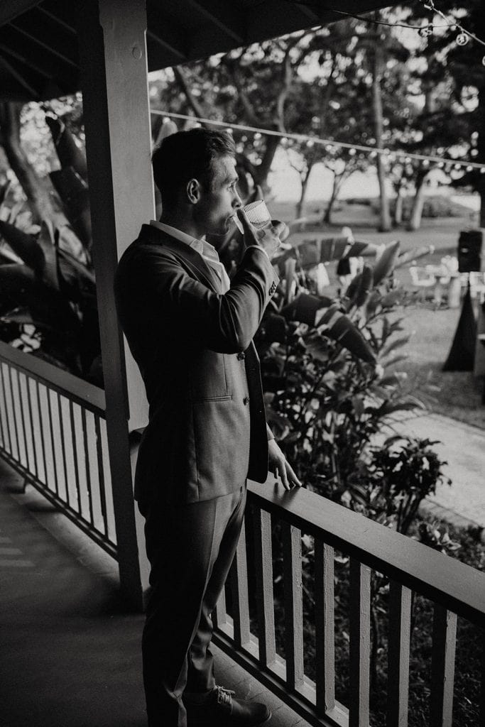 groom drinking cocktail on porch