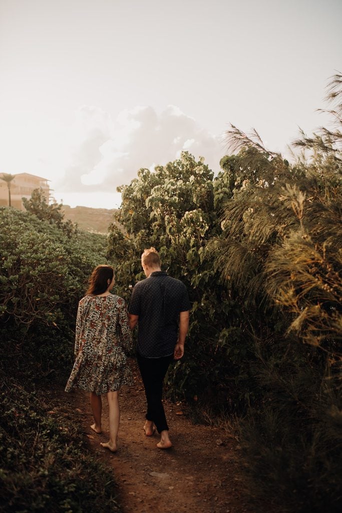 couple holding hands walking through greenery
