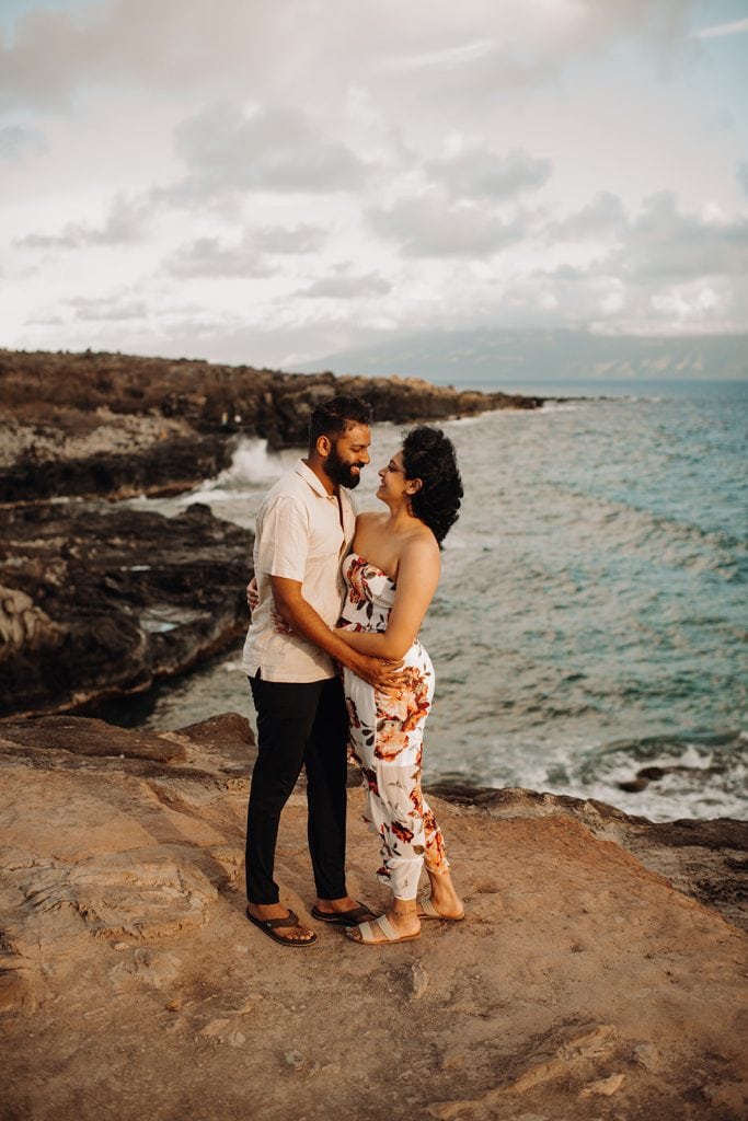man and woman standing on a cliff in hawaii