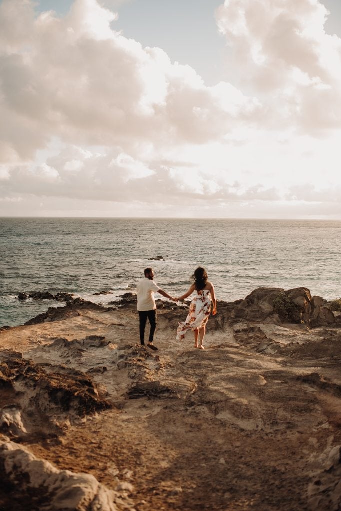 man and woman standing on a cliff in hawaii