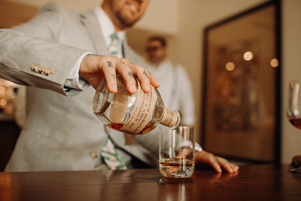 groom pouring a glass of whiskey before wedding ceremony