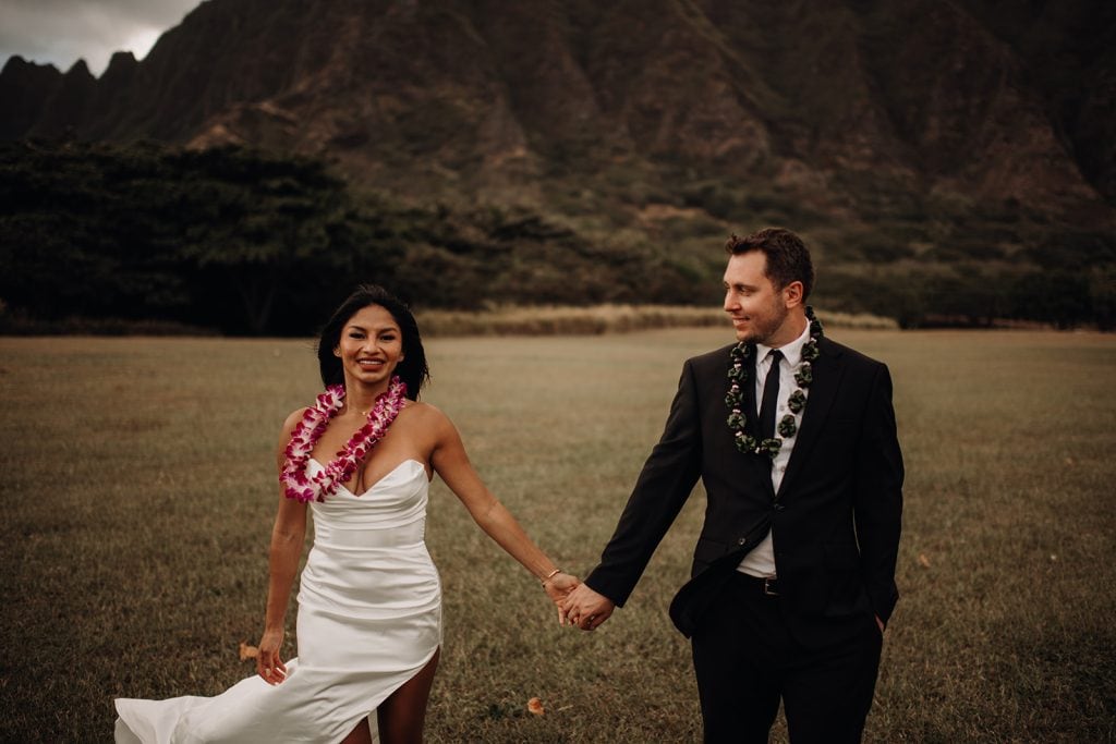 A blissful couple captured in a post-wedding photoshoot at Kualoa Regional Park, with the stunning backdrop of the Ko’olau Mountain Range.