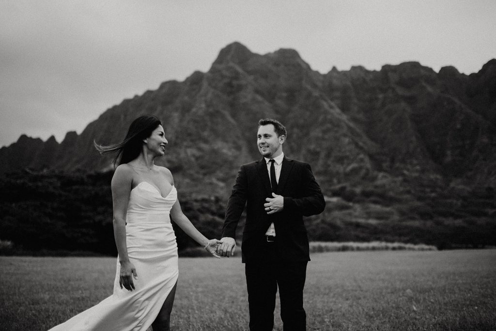A blissful couple captured in a post-wedding photoshoot at Kualoa Regional Park, with the stunning backdrop of the Ko’olau Mountain Range.