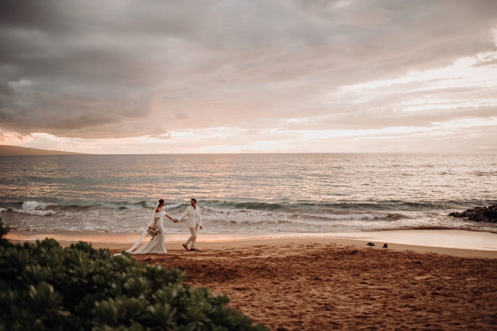 Bride and groom's romantic stroll along the shoreline, capturing the essence of their love story in Maui.