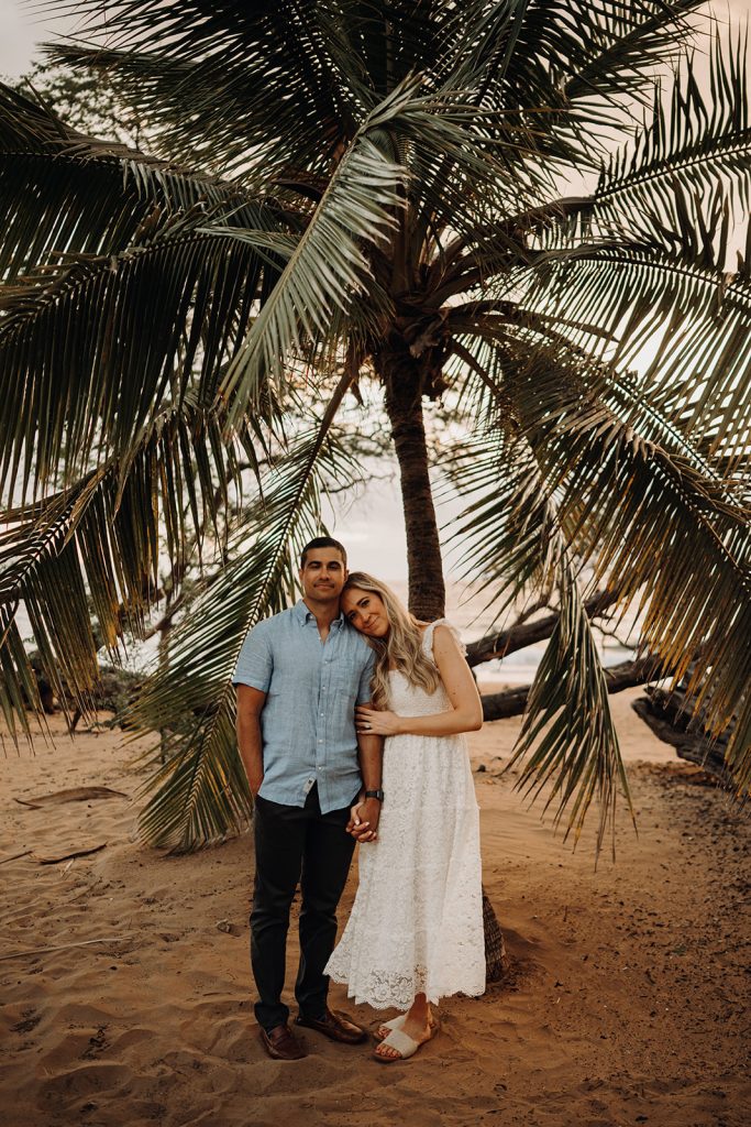 Couple stands under a palm tree on Po'olenalena Beach