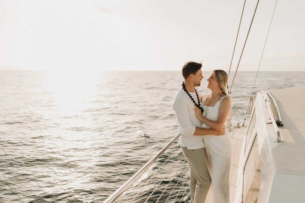 couple standing on side of the boat out at sea for sunset cruise