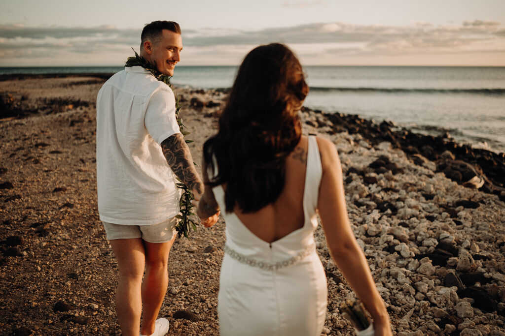 Bride and groom stand on a rock way near the pacific ocean